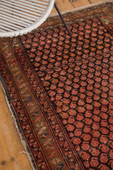 Vintage hand-knotted Hamadan rug showing traditional multi-color border pattern and tattered side.