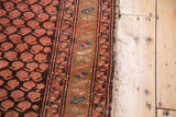Tattered side of a Vintage Hamadan rug, highlighting cranberry blush and charcoal brown patterns.
