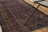 Vintage Belouch rug with distressed indigo and brown crab pattern, showing foundation.