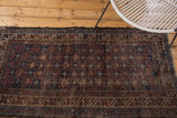 Distressed indigo and brown vintage Belouch rug showing crab design in diagonal lattice.