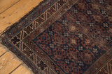 Distressed fringe and geometric border of a vintage Belouch rug in indigo and chestnut tones.