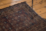 Distressed edge of a vintage Belouch rug, with visible tatter and geometric border.