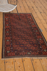 Corner of vintage Afghan rug with brick red gul motifs, navy, and charcoal crab border.