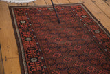 Vintage Afghan rug's repeating gul motif, geometric crab border, and time-softened brick red hues.