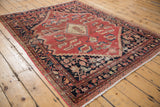 Distressed cinnabar red field, charcoal border, and fringed end of a vintage Malayer rug.