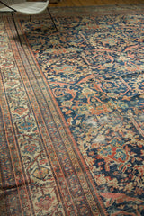 Worn navy field, intricate floral pattern, and striped border on an antique Mustafi Mahal carpet.