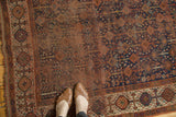 Distressed pile of an antique Kamseh rug, with plant, animal, and serpent motifs on indigo.