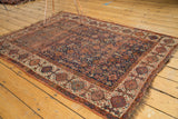 Antique Persian Kamseh rug's geometric border in beige, madder root red, and blue with tattered fringe.