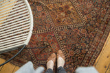 Antique Qashqai rug's intricate madder red, indigo, gold geometric pattern with aged texture.