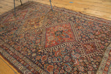 Antique Qashqai rug's madder red medallion with hook and latch motif, showing time-softened indigo and saffron.