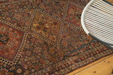 Antique Qashqai rug's intricate tribal patterns in madder red, indigo, and saffron gold tones.