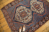 Vintage Afshar rug corner, featuring indigo field, terra cotta border, and repeating tribal motifs.