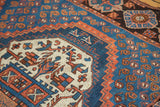 Close-up of Afshar rug's intricate ivory medallion with vibrant blue and orange geometric patterns.