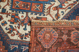 Afshar rug fold revealing intricate rectilinear motifs in madder root rust and blue.