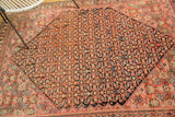 Antique Malayer rug corner detail, highlighting blush Herati motif transitioning to a dark indigo geometric field.