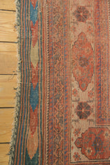 Tattered fringe and tribal striped edge of an antique Afshar rug with distressed red and blue boteh.
