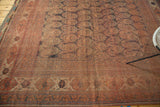 Distressed antique Afshar carpet with madder red field, oversized paisley boteh, and worn edge.