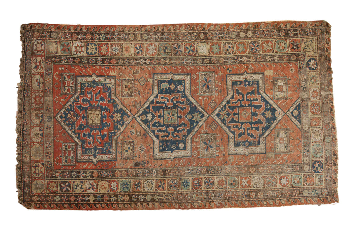 Antique Persian Soumac carpet, triple navy starburst medallions on a terra cotta field.