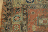 Geometric star motifs in dark Soumac border alongside a faded terra cotta field.