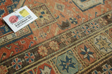 Close-up of antique Soumac's hand-woven geometric starbursts in terra cotta, navy, ivory.