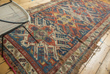 Geometric eagle pattern on antique Soumac rug in navy, red, saffron, with visible wear.