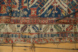 Tattered edge of an antique Persian Soumac rug showing exposed foundation and vibrant geometric patterns.