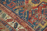 Geometric patterns in gem-tone navy, red, yellow on an antique Soumac rug with visible foundation.