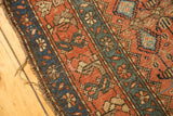 Hamadan runner end detail: terracotta blush, blue germinating flowers, and tattered edge.