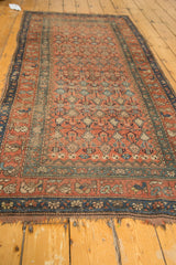 Antique Hamadan rug close-up: tattered fringe, dark blue border, and terra cotta blush field.