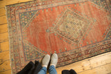 Antique Fereghan rug corner showing blush peach field, teal floral border, and storied wear.