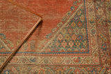 Antique Fereghan rug corner featuring blush peach florals, teal spandrel, and visible wear.