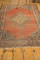 Mostly secure, fringed end of the antique Fereghan rug, revealing blush peach and teal tones.