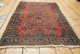 Vintage Lilihan rug corner with intricate navy border, cinnabar red field, and visibly tattered fringe.