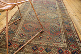 Vintage Kurdish rug with repeating geometric motifs in madder red, blue, and brown tones.