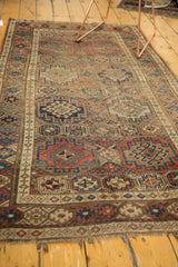 Distressed geometric gul and panel motifs in madder red, navy, beige, and brown, with fringe.