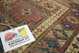 Madder red, blue, and brown geometric gul motif on a distressed vintage Kurdish rug.