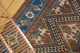 Intricate geometric patterning in navy, bronze, sand, and pale blush on the Hamadan rug.
