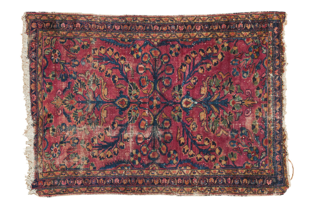 Vintage Lilihan rug, raspberry red field with allover navy and gold floral bouquet, decorative distress.