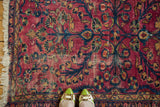 Distressed Lilihan rug field, highlighting raspberry red floral bouquet and budding plants.
