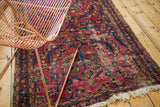 Vintage Lilihan rug's distressed raspberry red field, navy floral motifs, and tattered fringe.