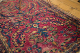 Distressed texture of vintage Lilihan rug, highlighting raspberry, navy, and gold floral patterns.
