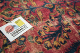 Close-up: distressed raspberry red vintage Lilihan rug with navy and gold floral motifs.
