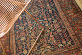 Antique Fereghan rug: intricate floral lattice on indigo field, classic madder red Samovar border.