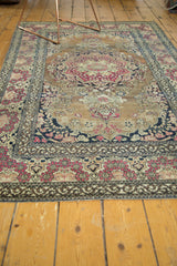 Antique Isfahan rug showing its rococo cochineal red floral border and intricate pale sand field.
