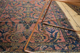 Blush vintage Lilihan rug corner with navy floral pattern, worn fringe, and metal frame.