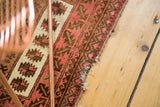 Tattered end and worn edging of a vintage Turkmen rug with blush and brown motifs.