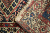 Vintage Borchalou rug's edge and fringe, revealing finely woven red, blue, and cream motifs.
