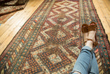Vintage Caucasian hand-knotted runner with diamond medallions, colorful botehs, and visible foundation wear.