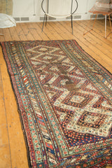 Detail view of a vintage Caucasian runner's geometric diamond medallions, colorful botehs, and areas of storied wear.