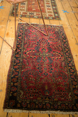 Vintage Sarouk rug's lower left, featuring cherry red field, dark navy floral border, and fringe.